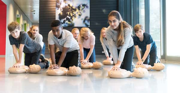 Studenci ćwiczący resuscytację krążeniowo-oddechową na fantomach do RKO w nowoczesnym obiekcie