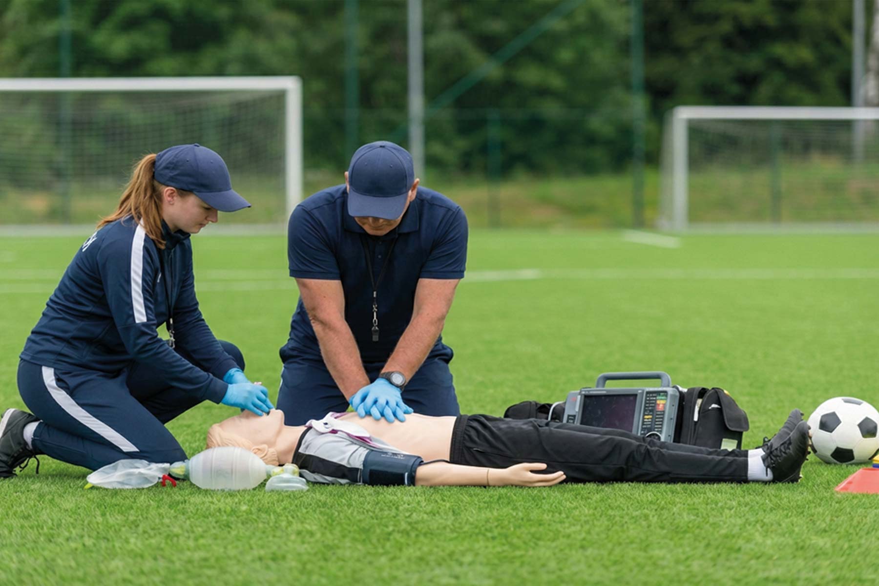 response team performing cpr with a manikin on a soccer field