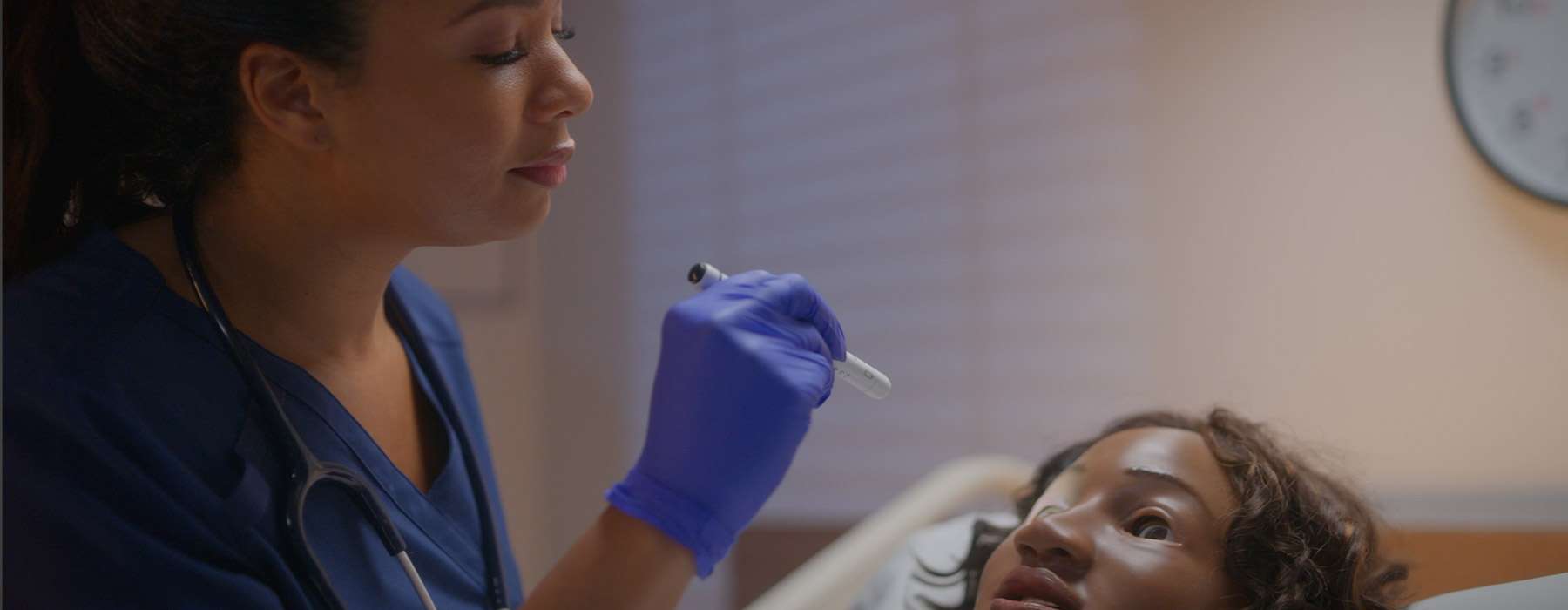 Nurse using MamaAnn to simulate checking dilating pupils