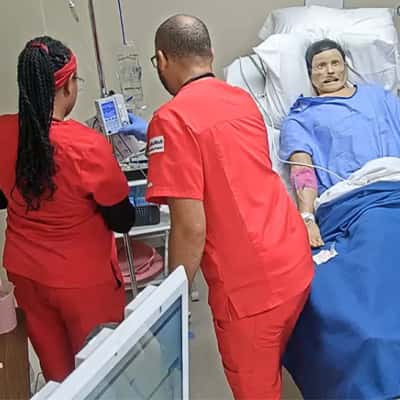 Male and female nurse in red uniforms working on a simulation