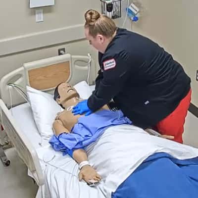Simulation training. A nurse performing cpr on a manikin.