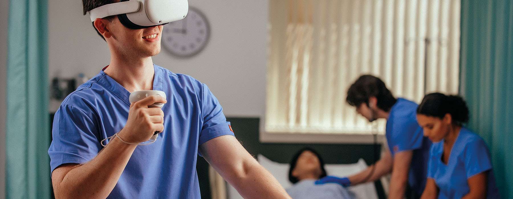 A nursing student smiling while using a VR headset to perform a virtual clinical assessment in a simulated hospital ward.