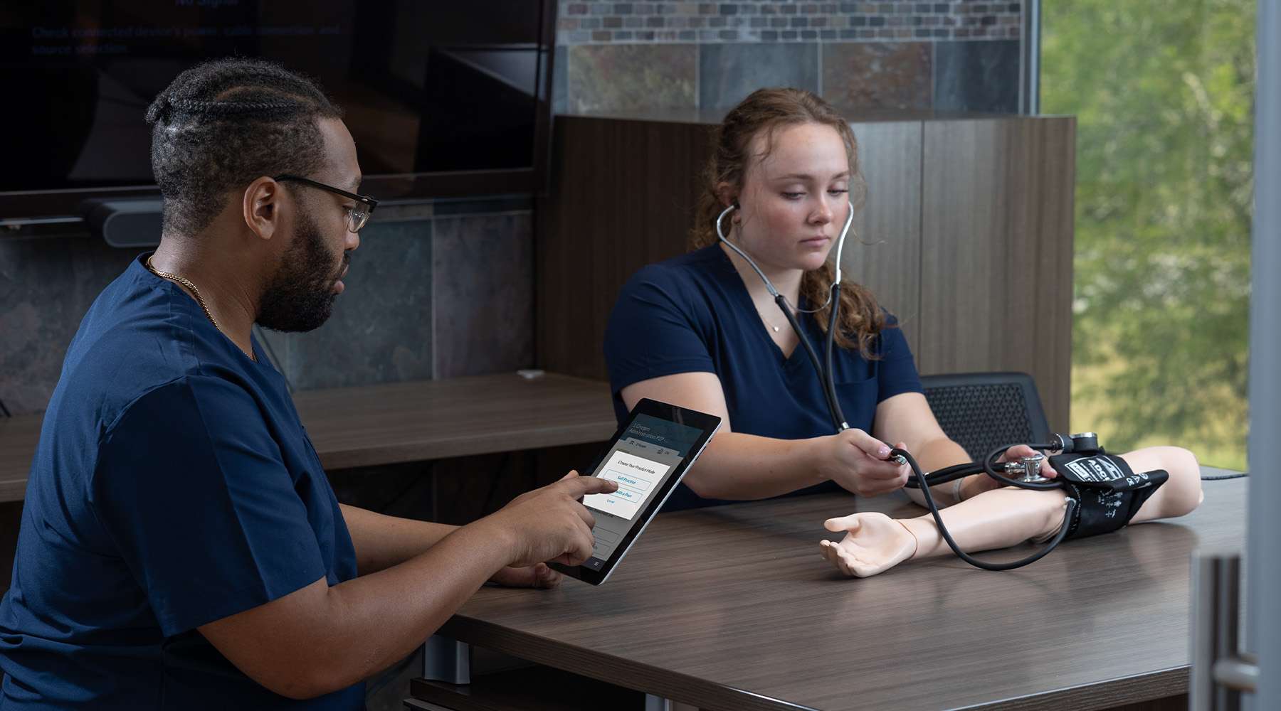 Two nurses in a meeting room using SimCapture for Skills with arm