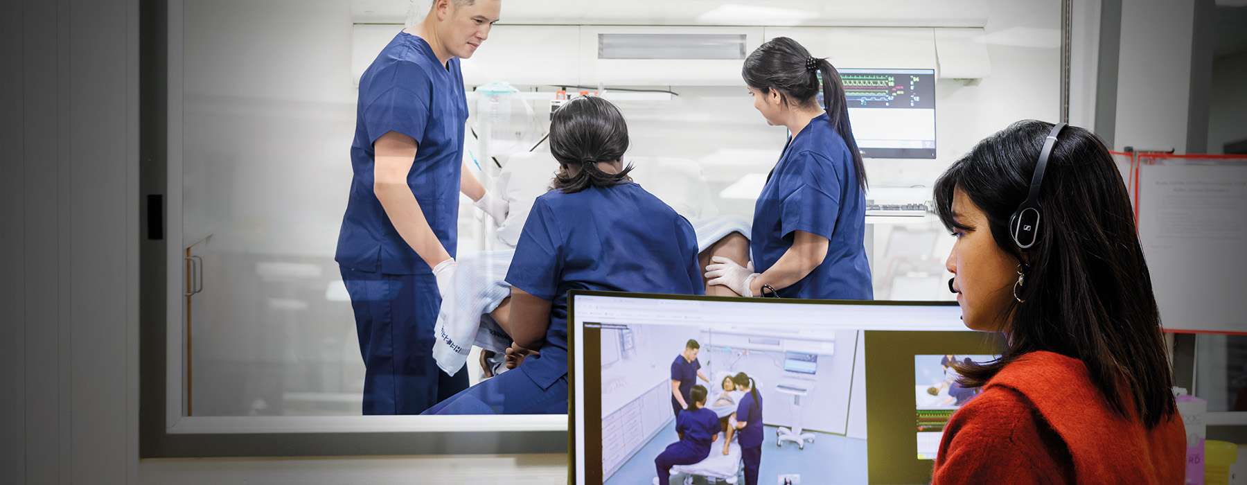 Woman reviewing an ongoing simulation training happening in a separate room.