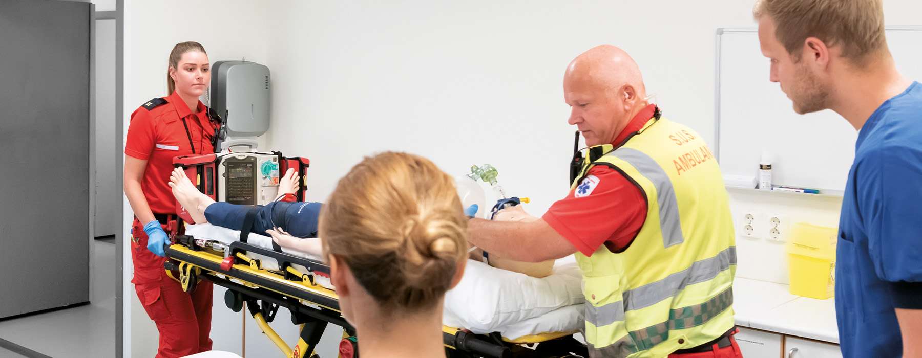 Team of ems moving a trolley with manikin and a nurse waiting