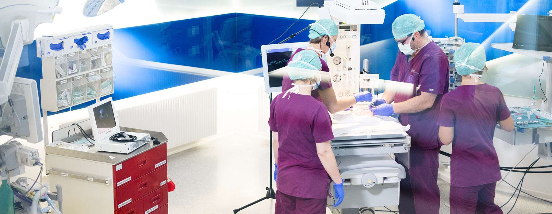 Operation room with four healthcare professionals working.