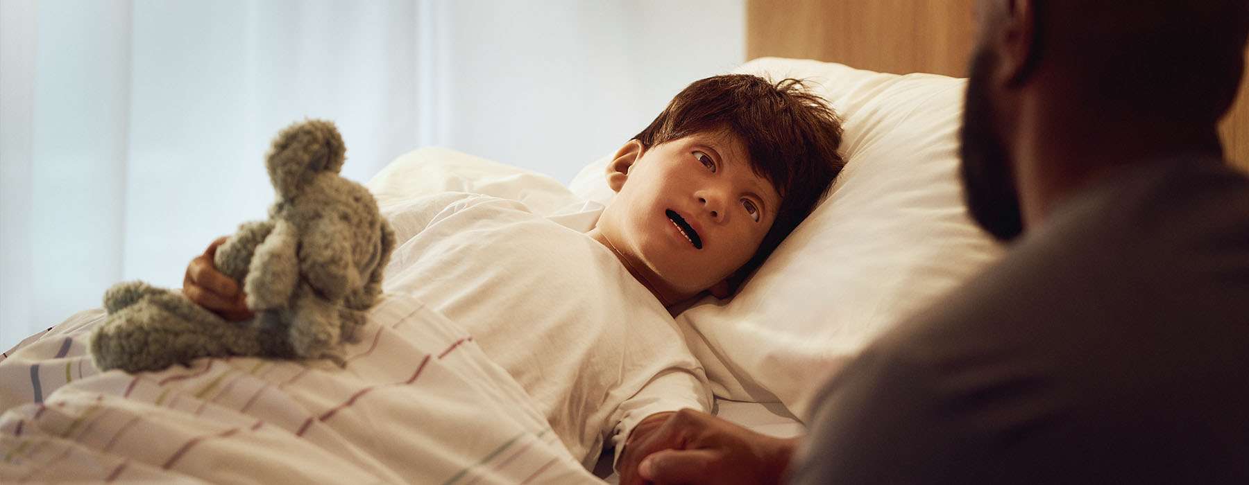 SimJunior manikin, turned towards a healthcare professional.