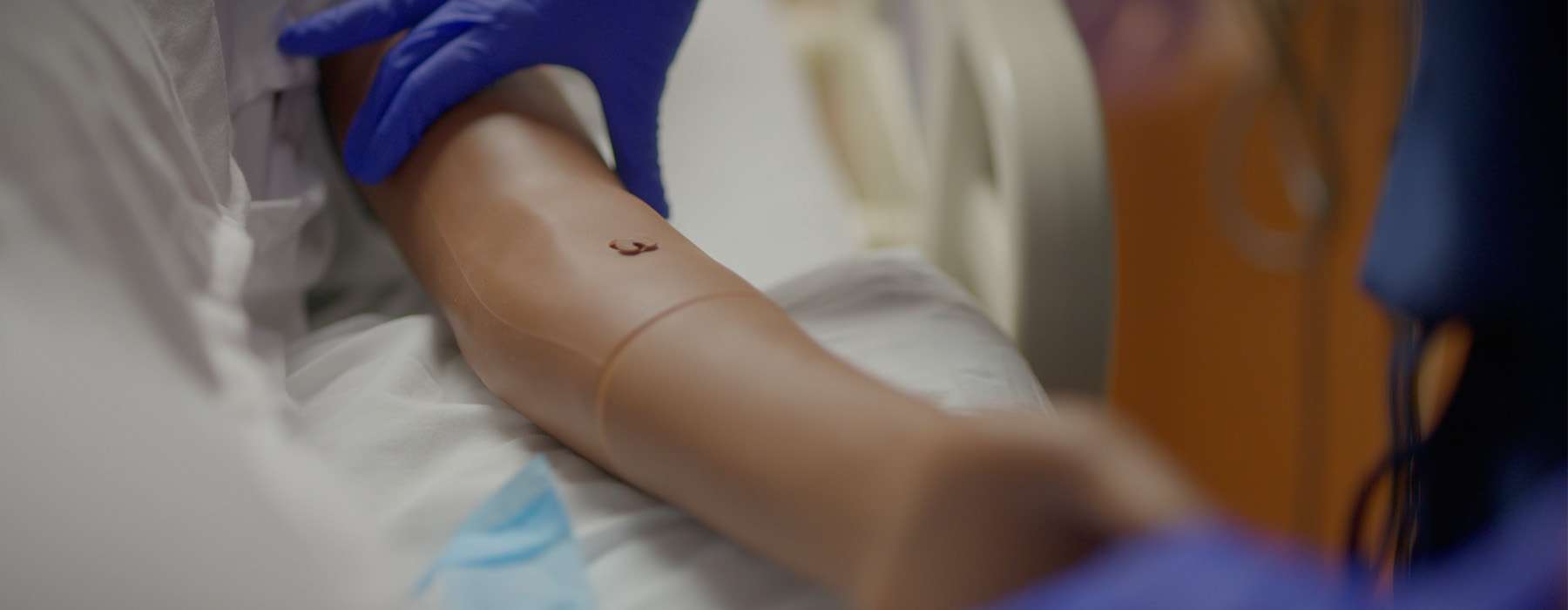 Close-up of nurse wearing blue gloves holding MamaAnne arm