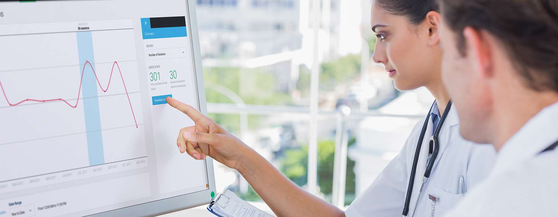 Two healthcare professionals reading and analyzing data on a screen.