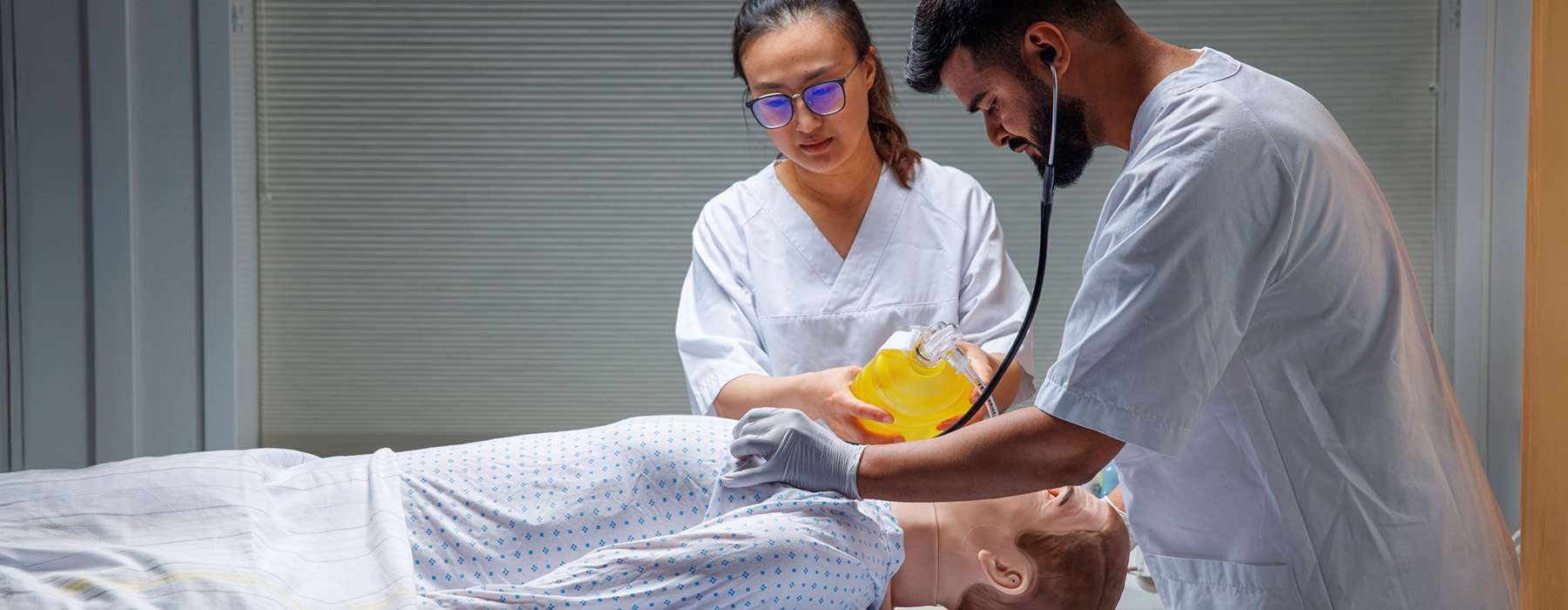 Two healthcare workers doing respiratory training on a manikin.