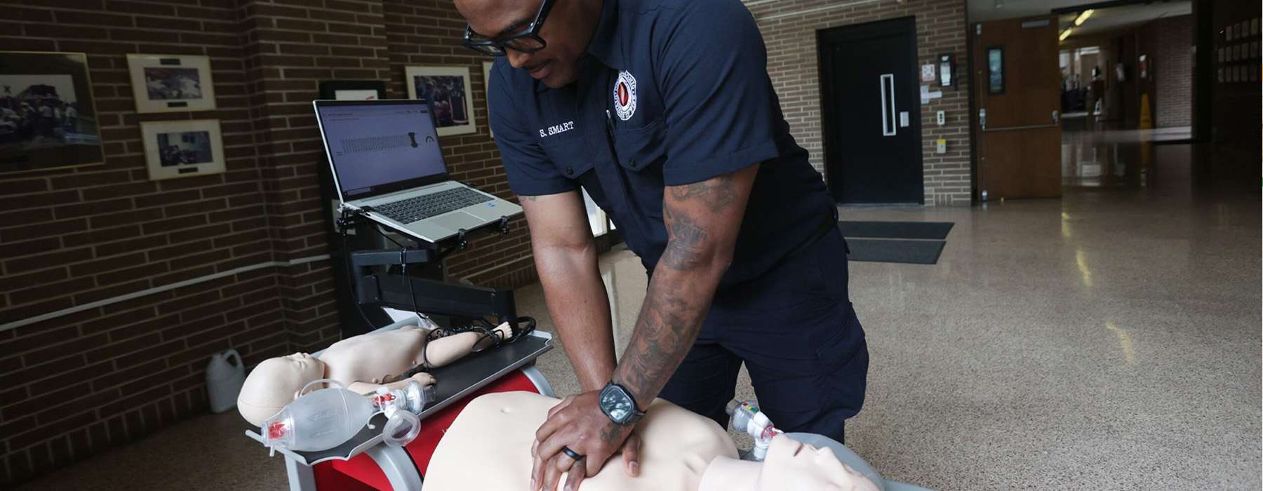 EMS worker performing CPR simulation training on manikin