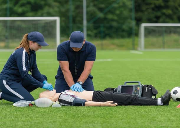 response team performing cpr with a manikin on a soccer field